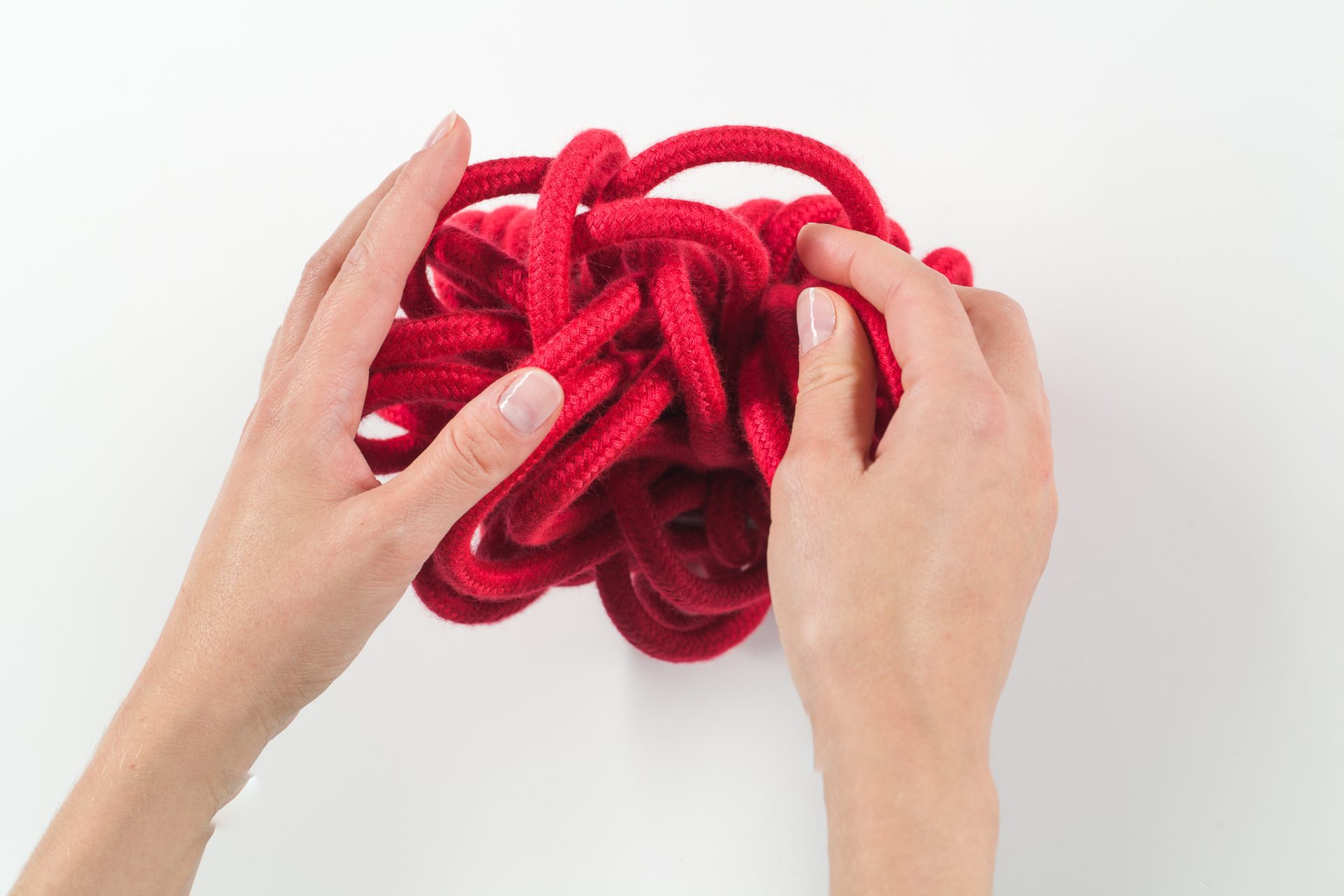 Two hands explore a red cotton ball.