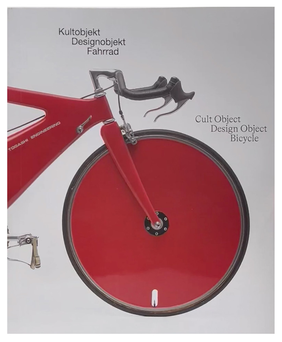 Cover of the exhibition catalog. The front half of a red bicycle can be seen on a white background. Above it is the title in black letters.