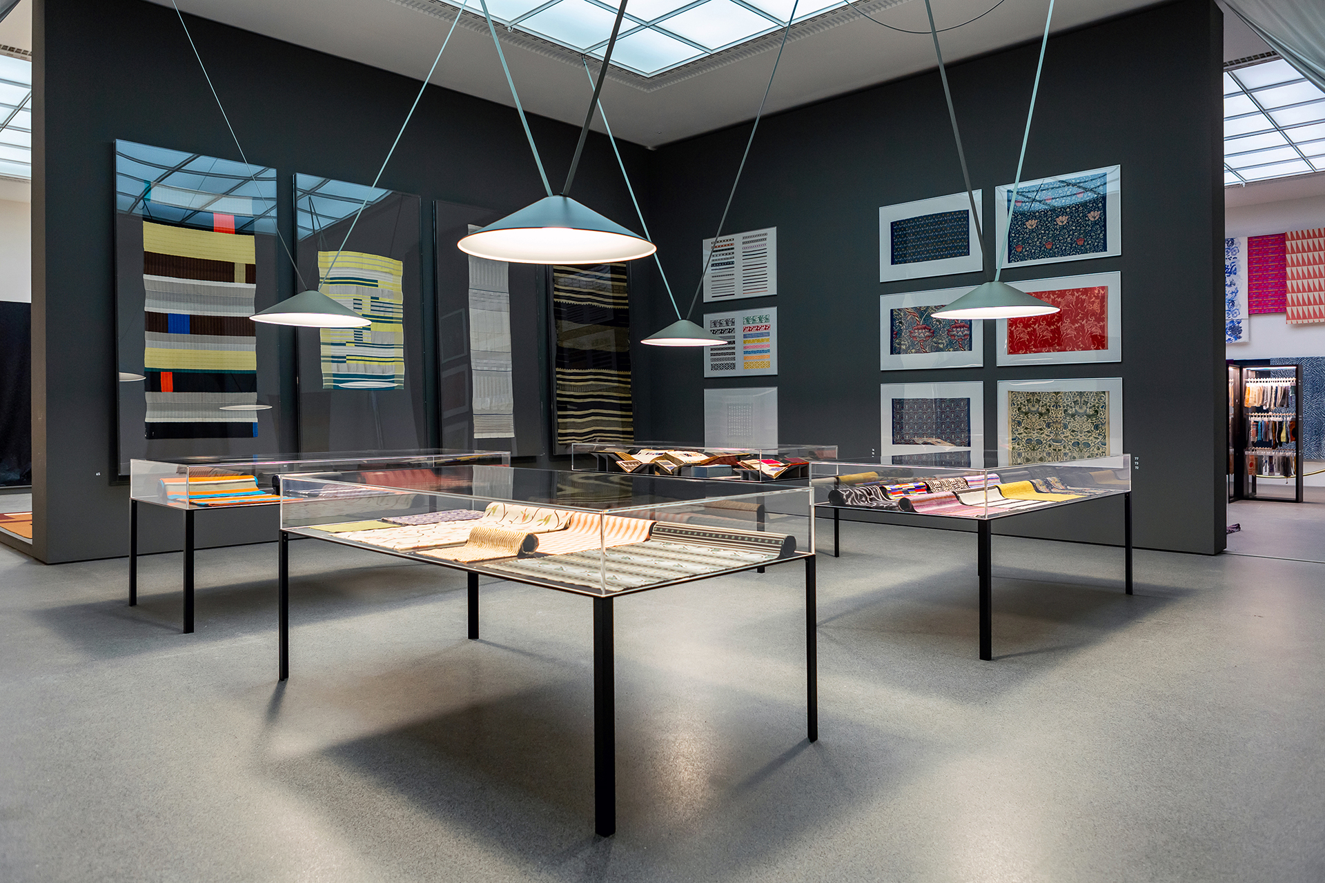 Four display cases with various fabrics, framed textiles on the walls