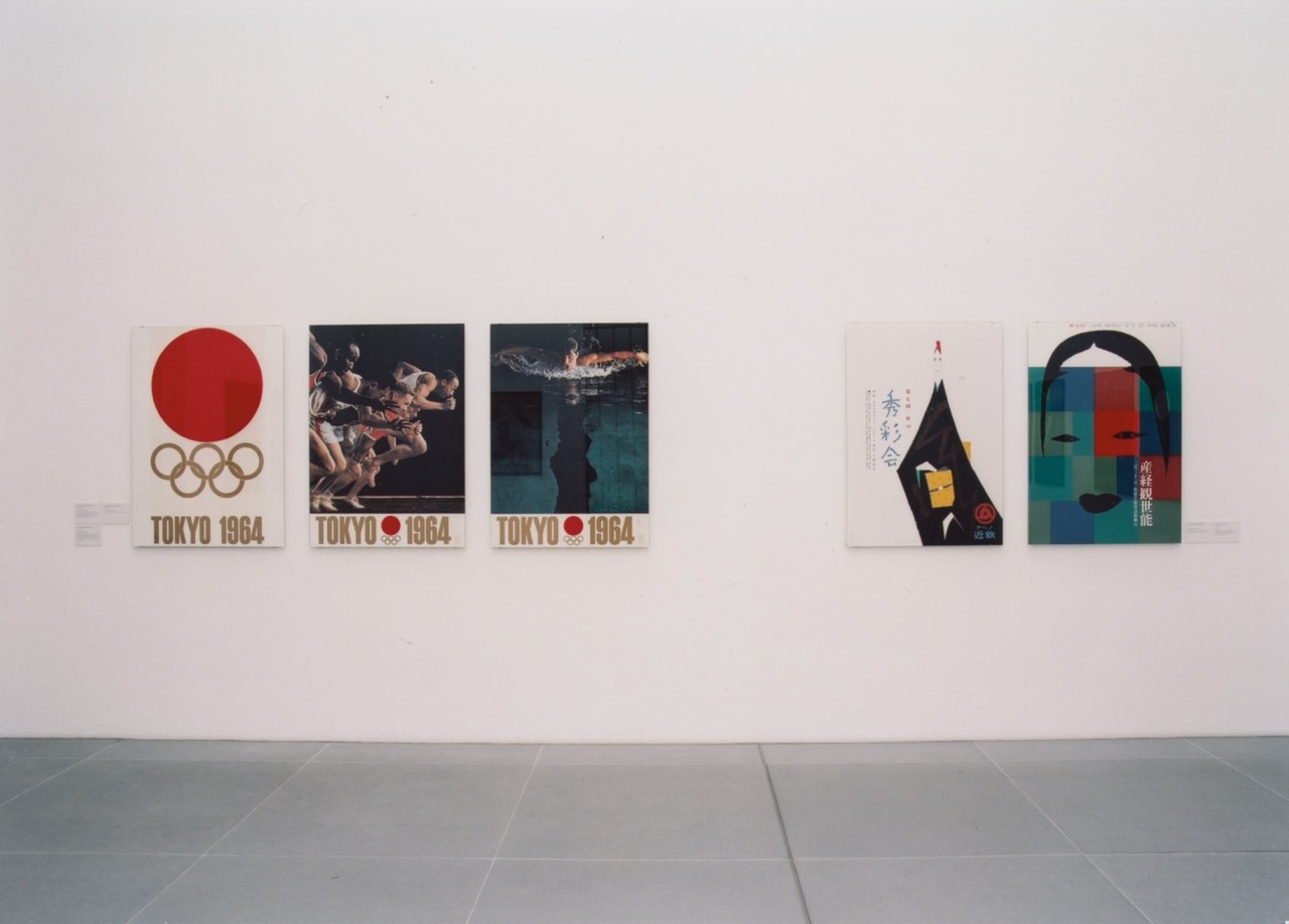 Links 3 farbige Plakate von den olympischen Spielen in Tokyo 1964. Olympische Ringe in Gold auf japanischer Flagge; Sprinter; Schwimmer. Rechts 2 weitere farbige Plakate.