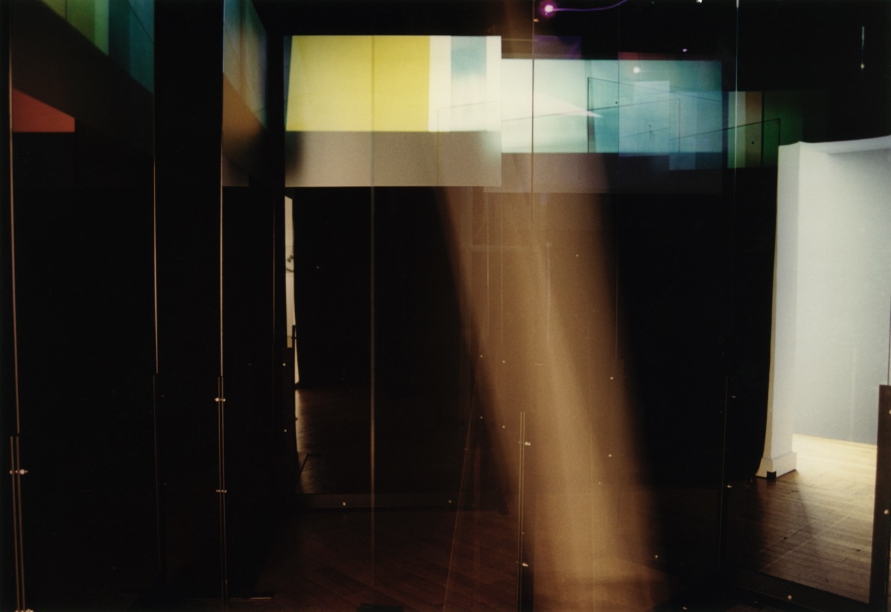 Dunkler Ausstellungsraum mit farbigen Folien an den Fenstern, durch die Licht einfällt