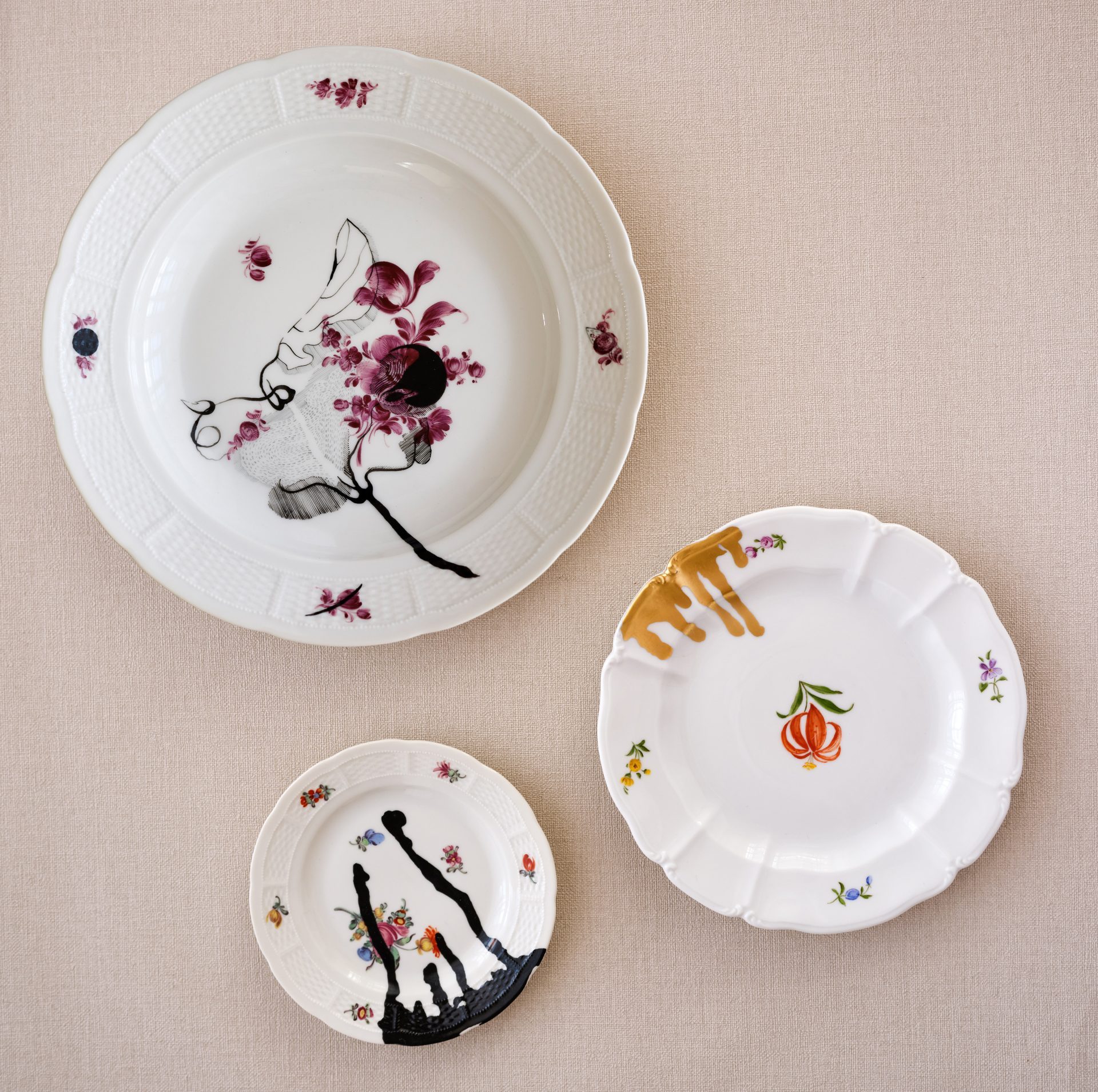 Drei unterschiedlich große Teller mit Blumendekoren, darüber gemaltes zweites Dekor