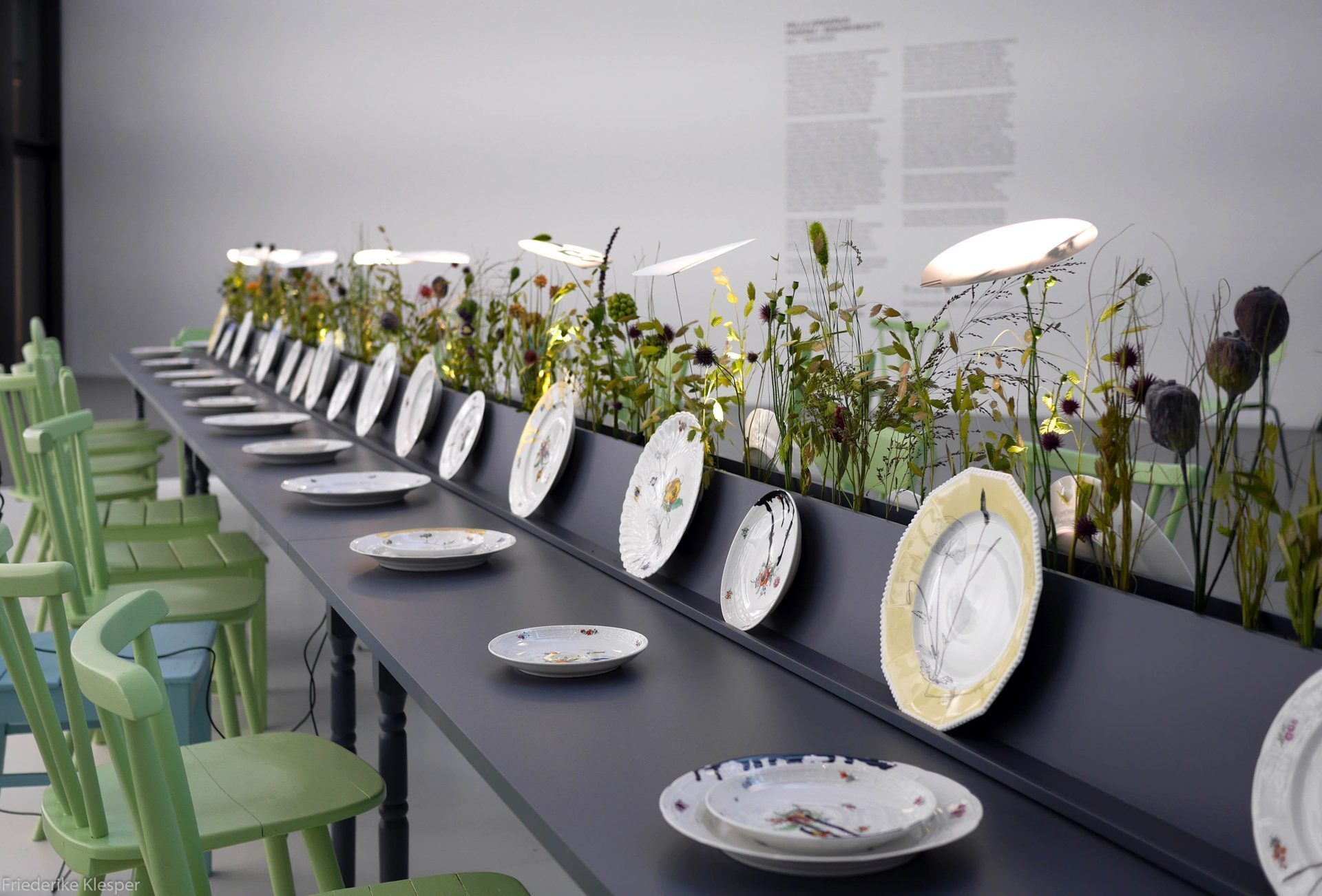 Tisch mit liegenden und stehenden Tellern, Blumendekoration und Leuchten, Stühle
