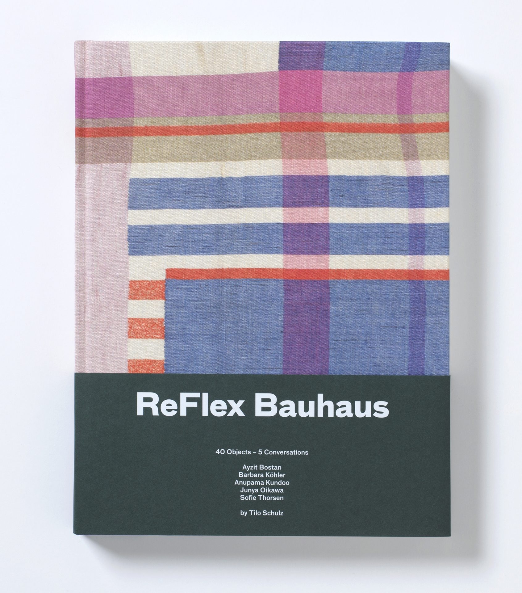 Stoff mit senkrechten und waagrechten Linien, die sich unregelmäßig überschneiden, sodaß sich Rechtecke bilden. Im unteren Drittel Papiermanschette, schwarze Fläche mit weißer Beschriftung: ReFlex Bauhaus.