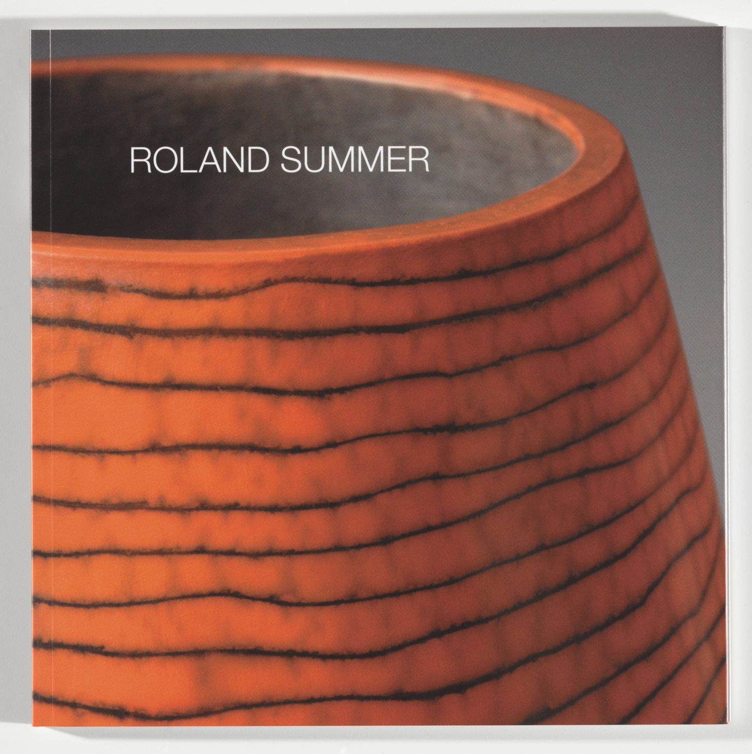 Stark angeschnittene, fast das ganze Bild einnehmende Vase, terracottafarben mit schwarzen leicht welligen horizintal verlaufenden Linien. Innenglasur, dunkelgrau, worauf die Beschriftung zu lesen ist: Roland Summer.