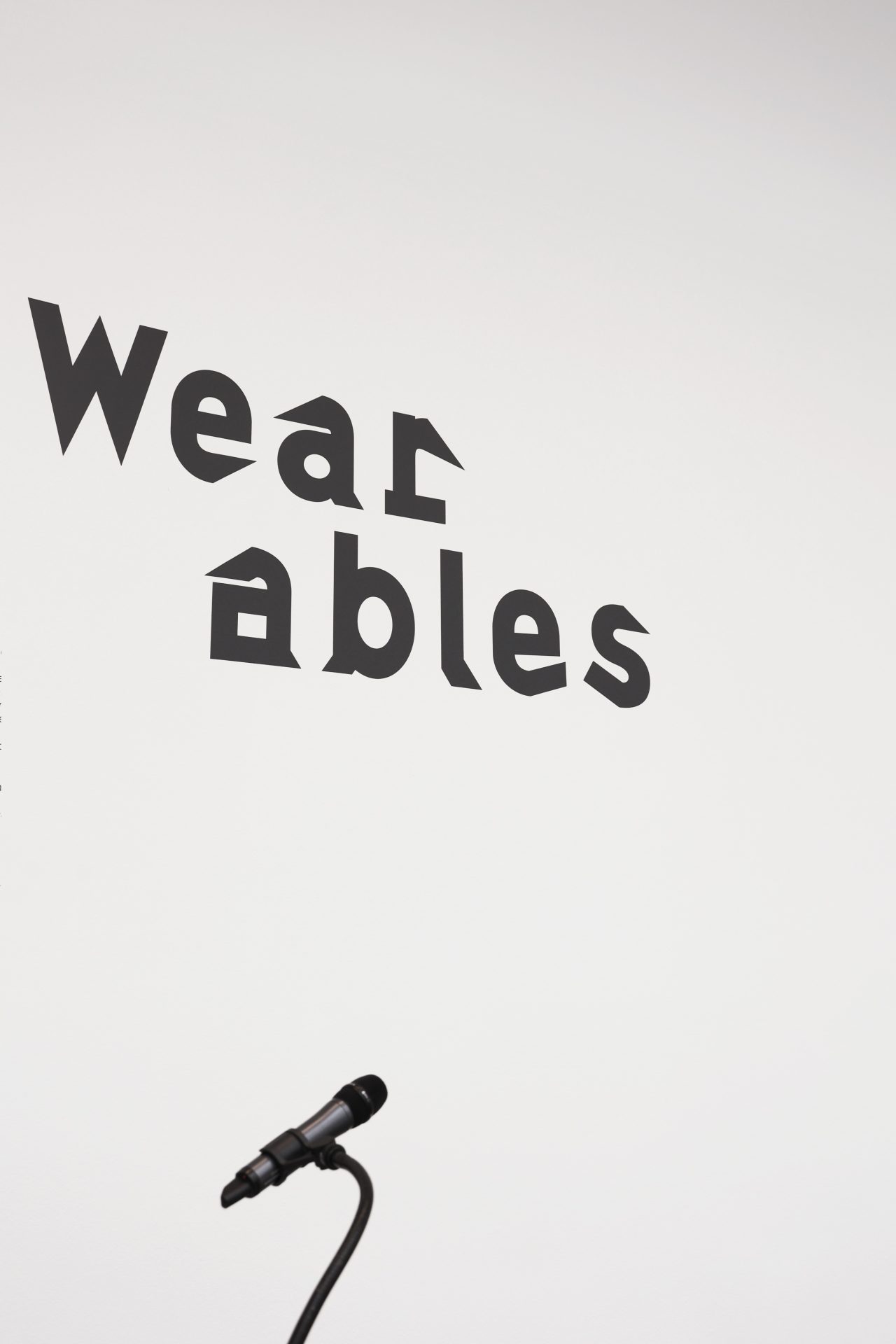 Wand mit Aufschrift. Der Titel Wear-ables ist zu sehen mit einem Mikrofon darunter.