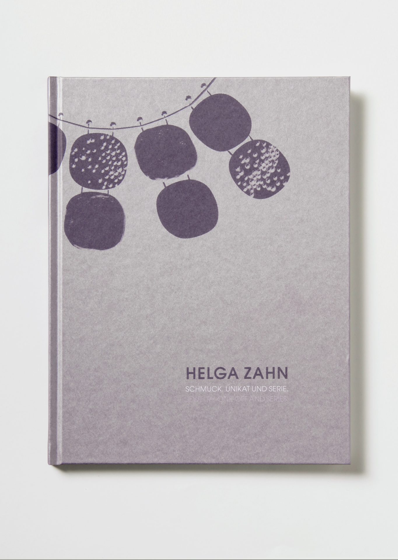 Parts of a necklace on a light grey background in the upper left corner: three elements on a wire, each consisting of two rounded rectangles joined together. Inscription at bottom right: Helga Zahn jewellery. Unique piece and series.
