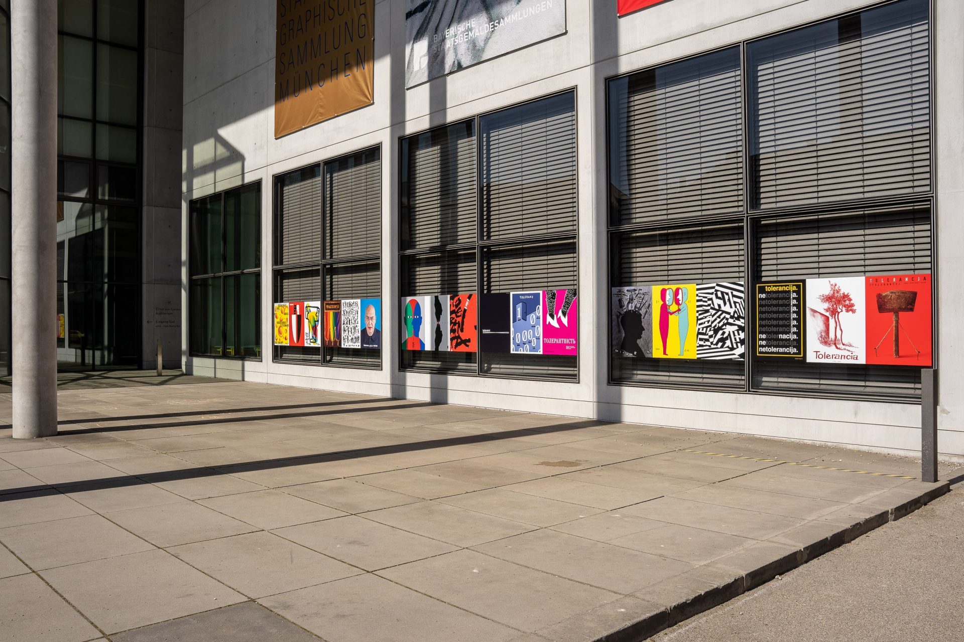 Entrance of the Pinakothek der Moderne. A series of colourful posters hang outside on the window.