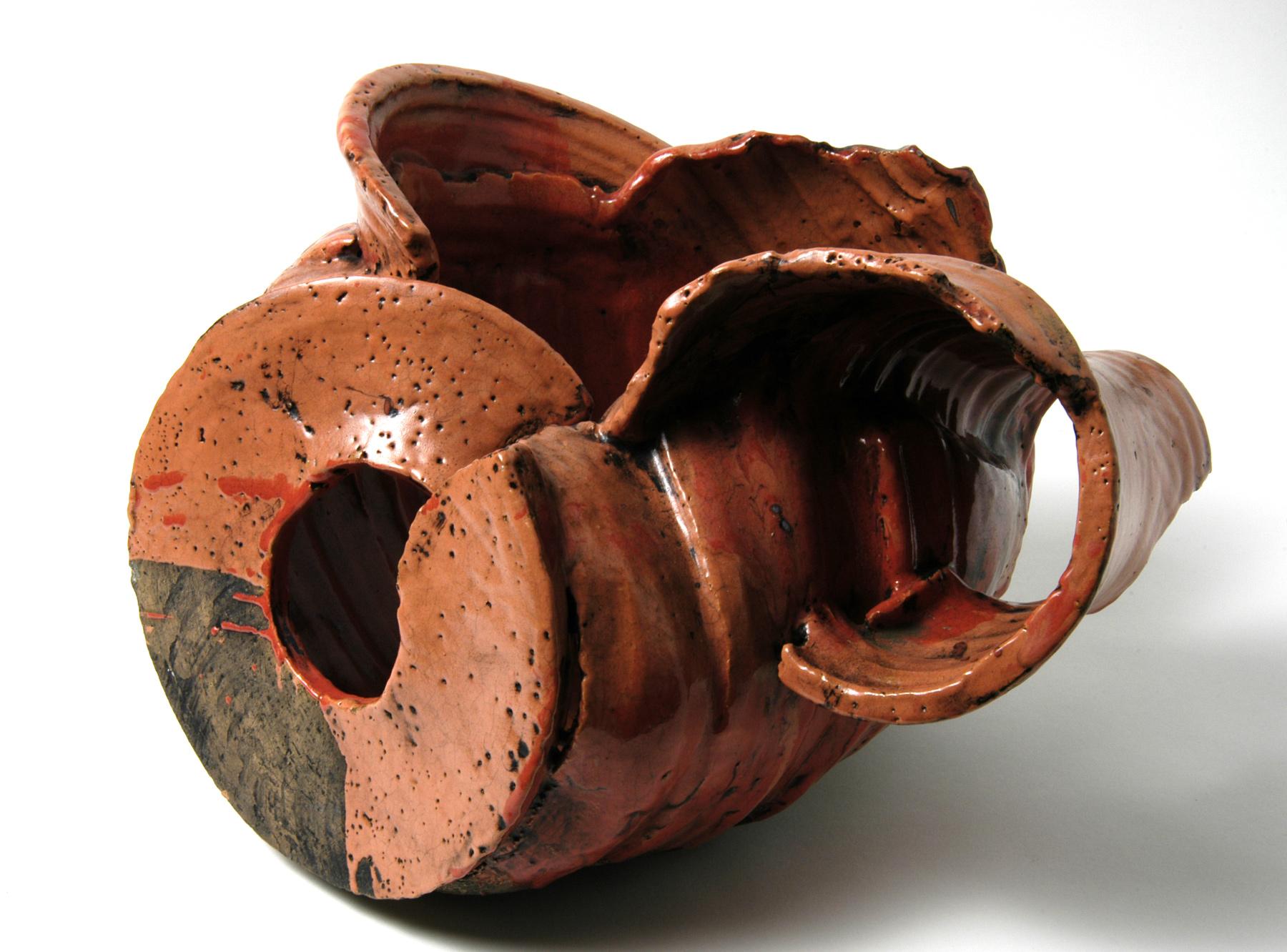 Organically shaped ceramic sculpture with an earthy, glossy glaze, irregular openings and a dynamic, twisted structure.