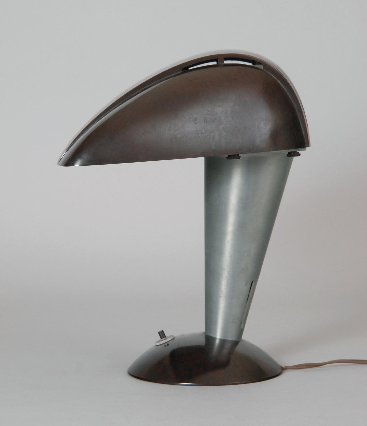 Metallic table lamp with futuristic, curved shade and small switch on the round base.