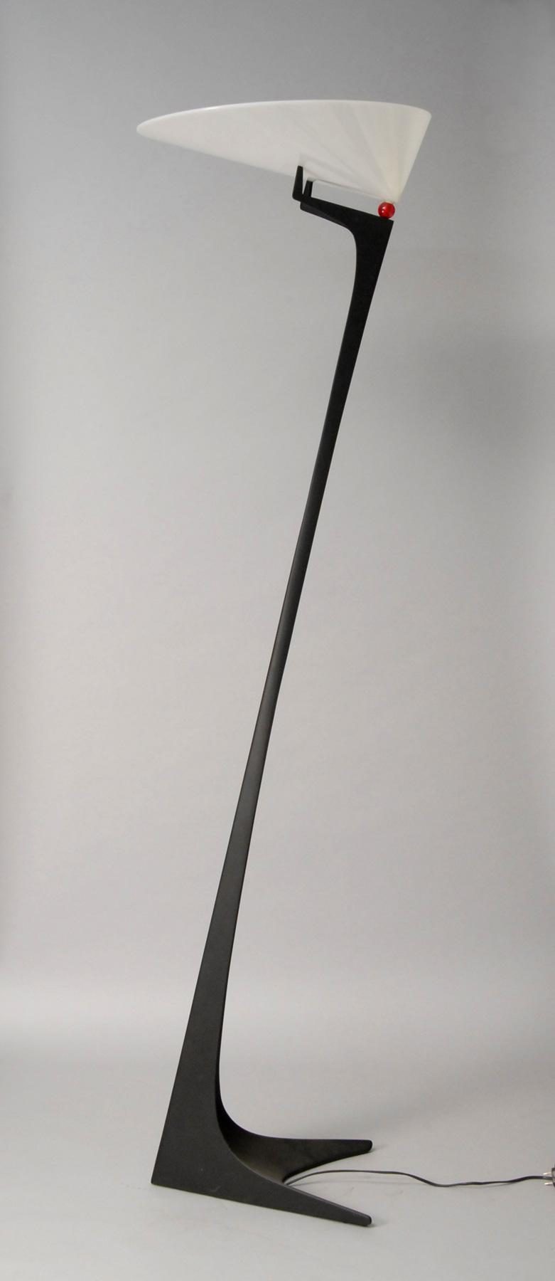 Slim, black floor lamp with slanted, white shade and red ball detail.