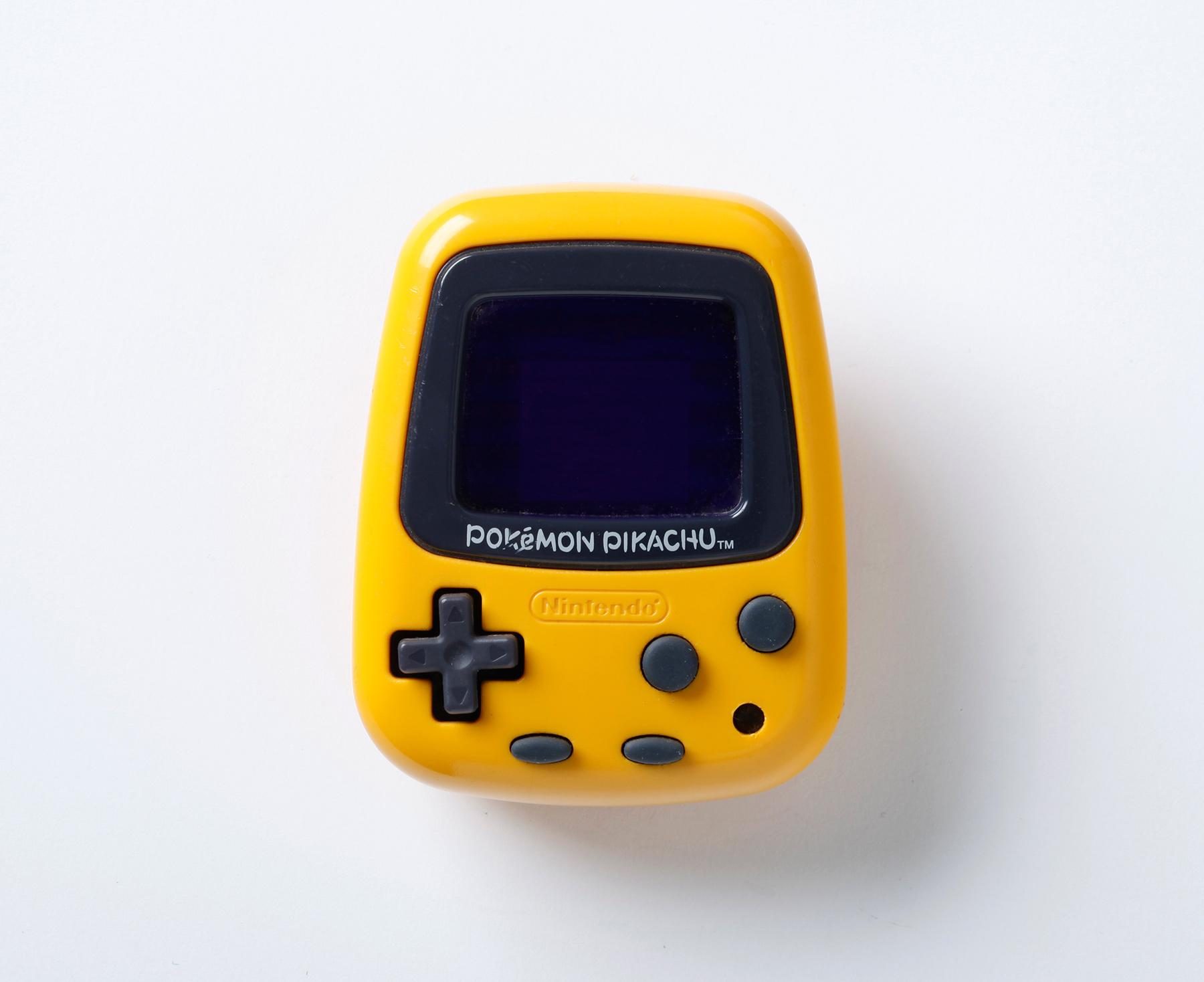 Yellow Pokémon Pikachu device from Nintendo with a small screen, control pad and several buttons. The ‘POKÉMON PIKACHU’ logo is under the display.