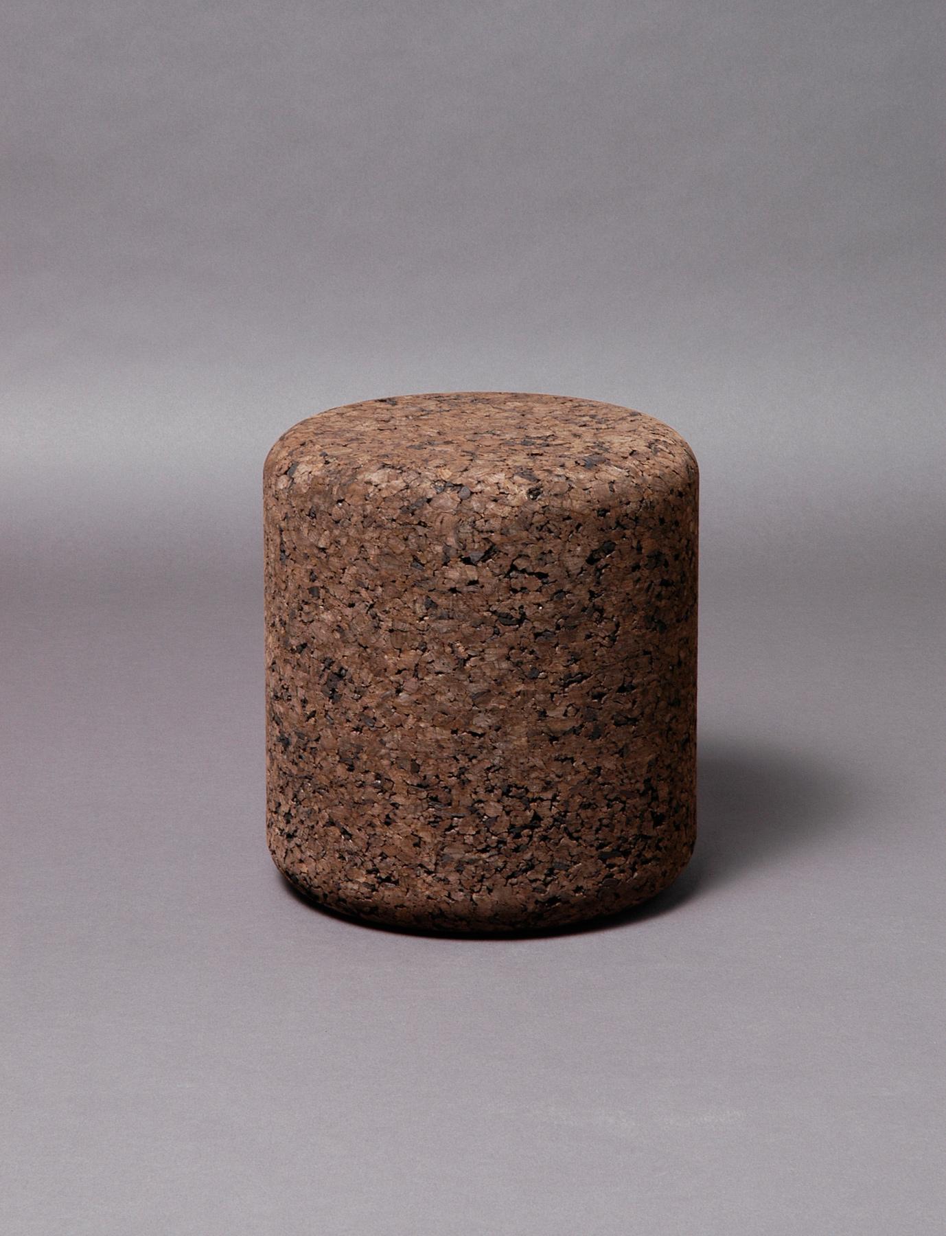 Cylindrical stool made of pressed cork with a natural, irregular texture in shades of brown.
