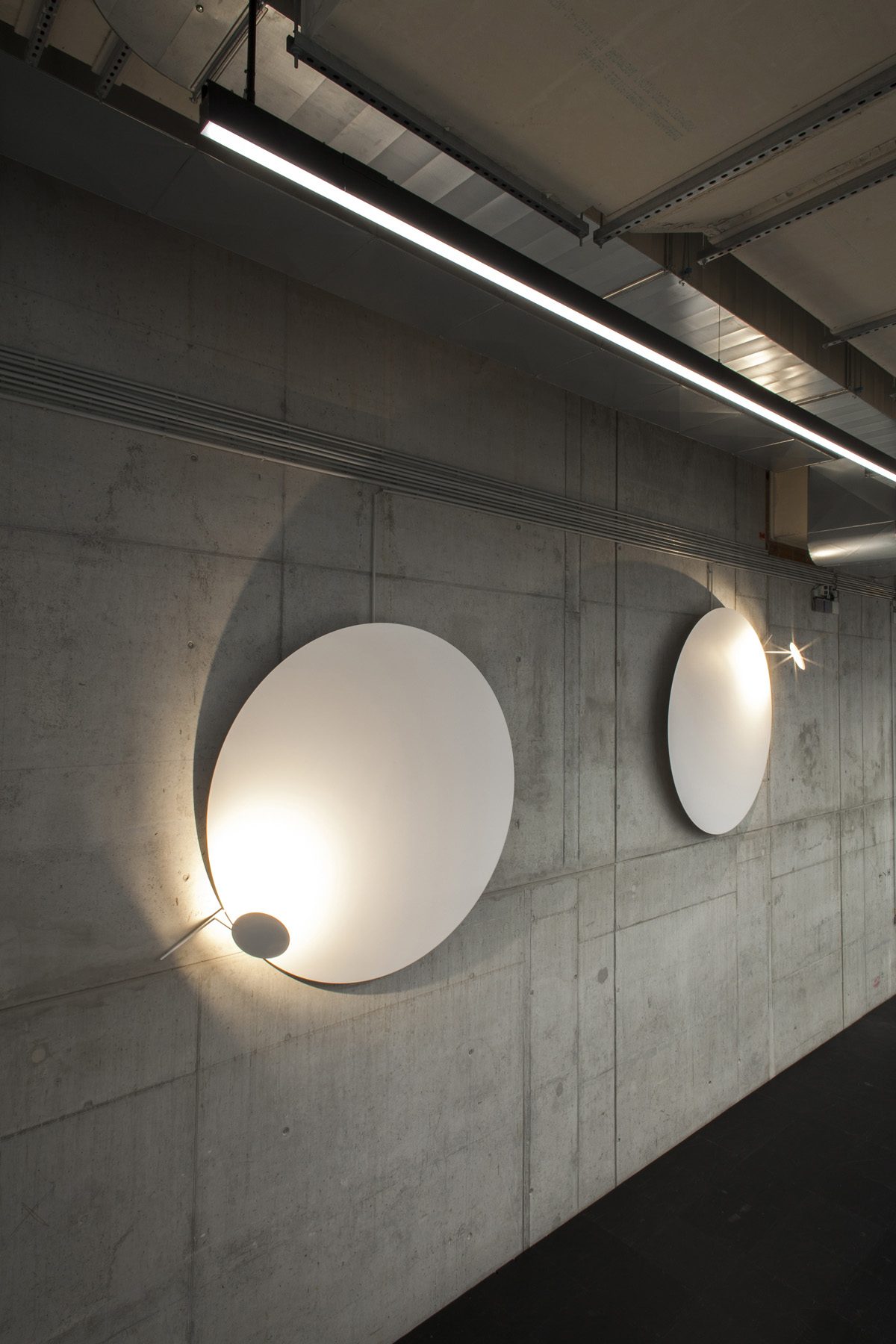 Round wall lights on a concrete wall create a gentle play of light and shadow.