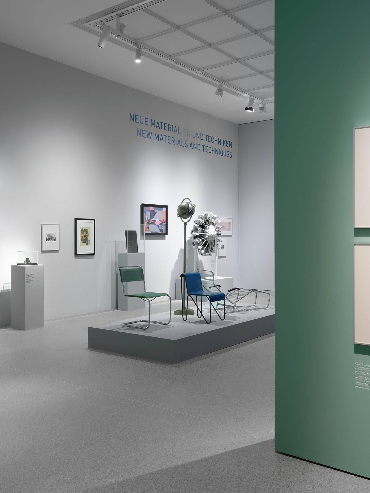 You can see the exhibition installation "4 Museums – 1 Modernism." In the foreground is a platform with Bauhaus chairs, loungers, and a lamp. Behind it is a "radial engine" and framed pictures.
