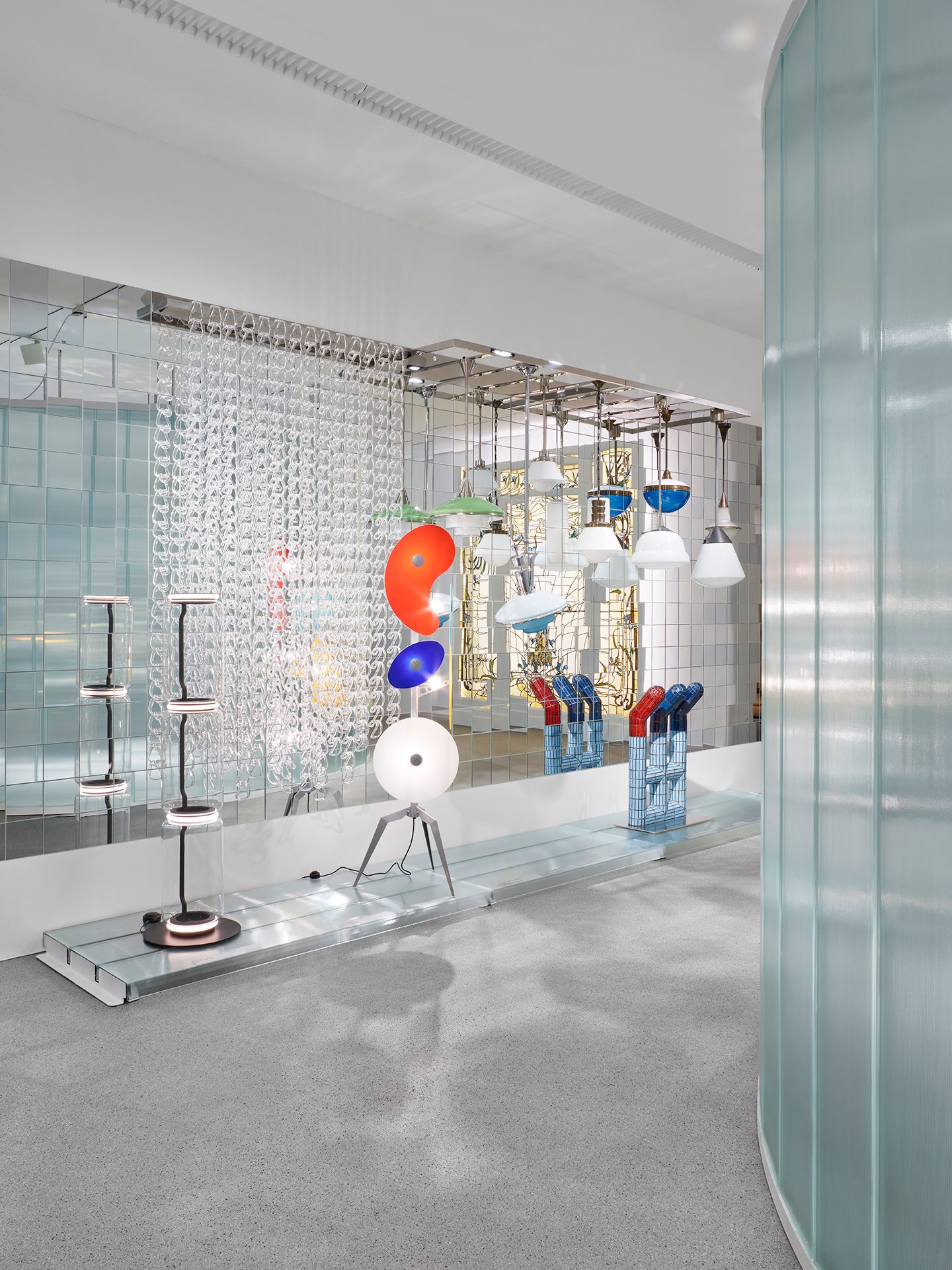Man sieht die Ausstellungsinstallation "Die Farbe von Glas" bestehend aus gläsernen Wand- und Bodenelementen in der verschiedene Objekte aus Glasgezeigt werden.