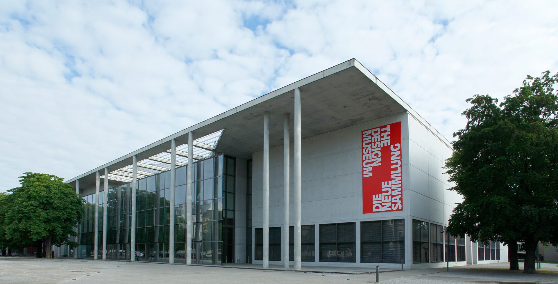 Außenansicht Pinakothek der Moderne bei Tageslicht mit rotem Werbebanner von Die Neue Sammlung.
