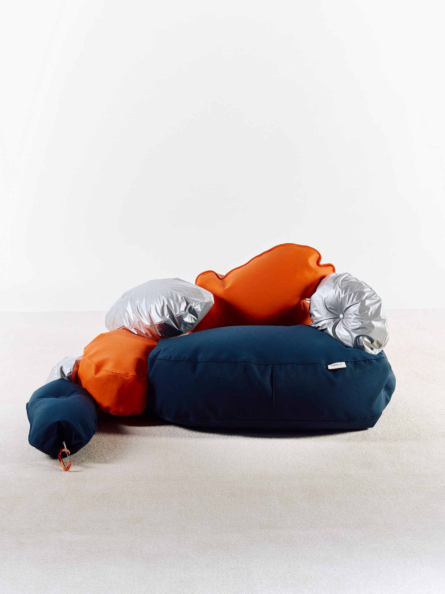 Sitzmöbel aus mehren kissenförmigen in silber, blau und orangfarbigen Elementen.