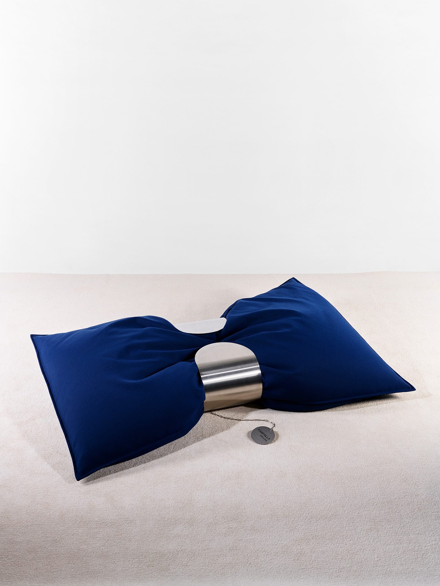 Blaues Sitzkissen das in der Mitte von einer Spange aus Metall gehalten wird.