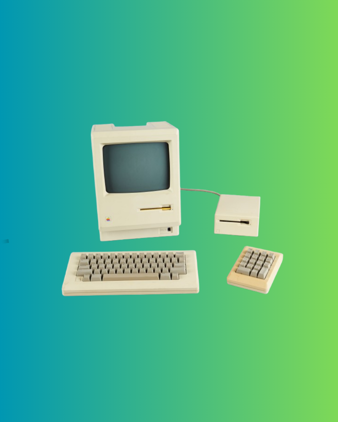 A cube-shaped computer with keyboards in the foreground and a floppy disk drive on the left.