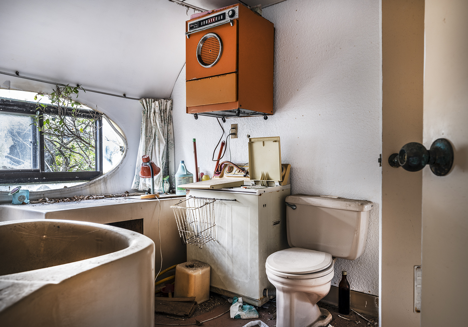 Interior view of the replica of the Futuro plastic house. A kitchen with an orange washing machine, toilet and kitchenette can be seen.