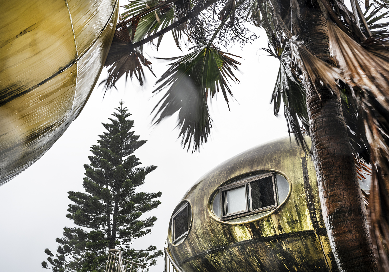 Detailed views of the replica of the Futuro plastic house surrounded by trees.