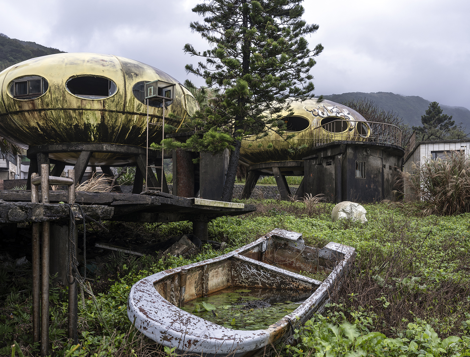 Two heavily weathered replicas of the Futuro plastic house with a boat wreck in the foreground.