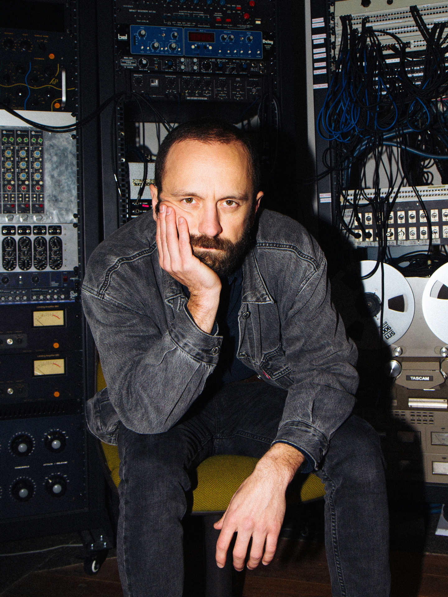 Der Musiker Ian Fisher sitzt mit aufgestützter Hand in einem Tonstudio